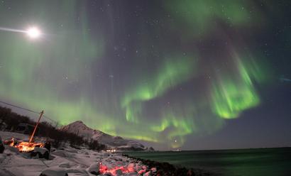 Northern lights over the campfire by the fjord