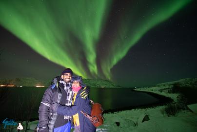 A happy couple by the fjord under the Northern Lights