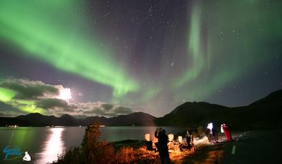 People on the beach under the sky of the moon and the Northern Lights