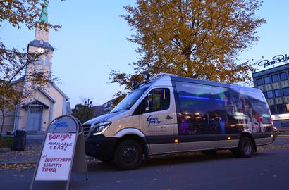 Minibus and a sales sign in front of the church. Autumn colors on the three.